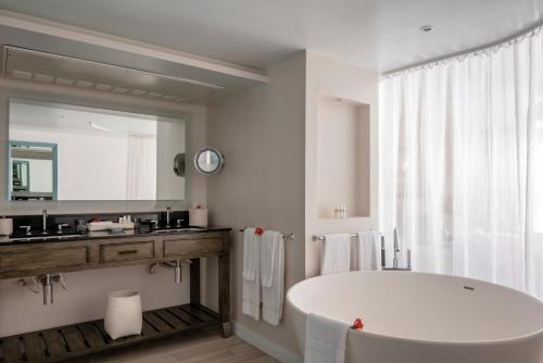 a white bathroom with a large tub and a mirror at BodyHoliday St Lucia in Gros Islet
