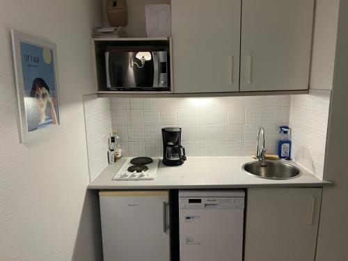 une petite cuisine avec un évier et un micro-ondes dans l'établissement SAVANNA BEACH I Agréable T2 avec belle vue mer piscine Rochelongue Cap d'Agde, au Cap d'Agde