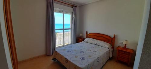 ein Schlafzimmer mit einem Bett und einem großen Fenster in der Unterkunft Apartamentos Puerto Mar V.v. in La Manga del Mar Menor