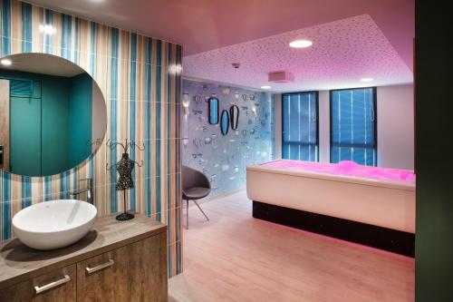 a bathroom with a tub and a sink and a mirror at DOMITYS La Courtine in Melun