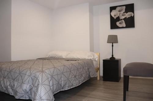 a bedroom with a bed and a lamp and a chair at Cozy place, 15 min to Niagara Falls & USA border. in Thorold