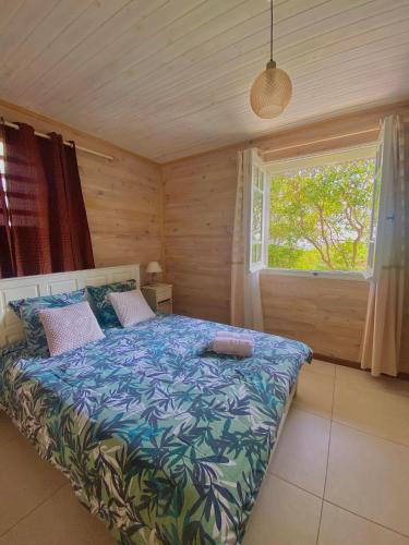 a bedroom with a bed in a room with a window at La casa de la plaine des cafres in Le Tampon