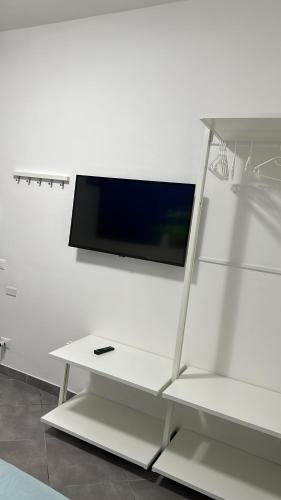 Elle comprend une télévision à écran plat sur un mur blanc. dans l'établissement Domora mini Apartament nicolò, à Ortona