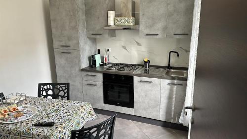 - une cuisine avec une table, une cuisinière et un évier dans l'établissement Domora mini Apartament nicolò, à Ortona