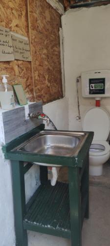 La salle de bains est pourvue d'un lavabo vert et de toilettes. dans l'établissement Gjipe Eco Campground, à Vuno