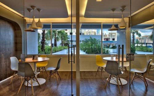 a restaurant with tables and chairs and a large window at FLATS - DUO JK in Sao Jose do Rio Preto
