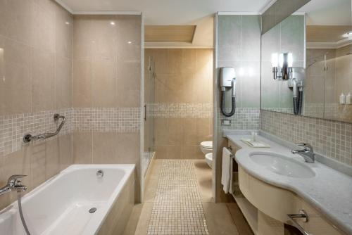 La salle de bains est pourvue de 2 lavabos, d'une baignoire et de toilettes. dans l'établissement UNAHOTELS Expo Fiera Milano, à Pero
