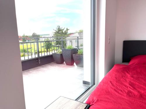 a bedroom with a red bed and a balcony at Weißes Haus in Gerasdorf bei Wien