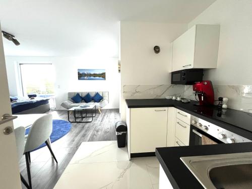 a kitchen with white cabinets and a living room at Weißes Haus in Gerasdorf bei Wien