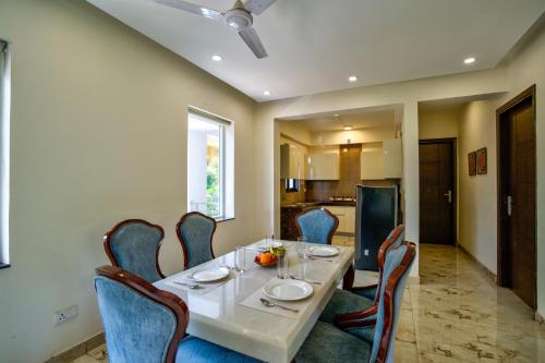 a dining room with a white table and chairs at Luxury 2BHK Apartment By Bluewave Hospitality in Candolim