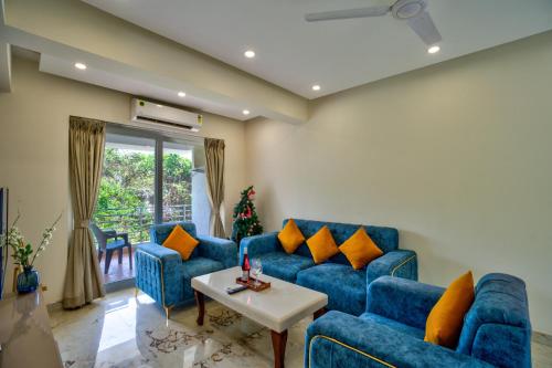 a living room with blue couches and a table at Luxury 2BHK Apartment By Bluewave Hospitality in Candolim