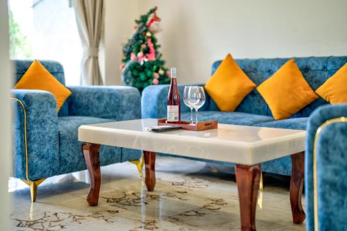 a living room with a couch and a table with a bottle of wine at Luxury 2BHK Apartment By Bluewave Hospitality in Candolim