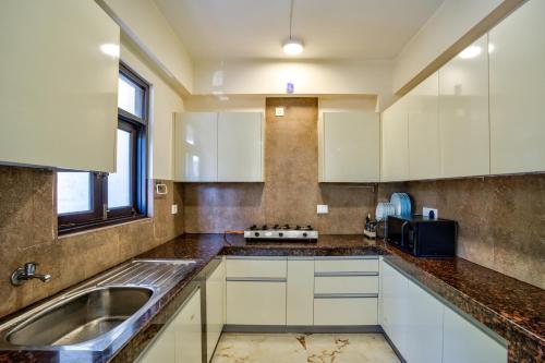 a kitchen with white cabinets and a sink at Luxury 2BHK Apartment By Bluewave Hospitality in Candolim