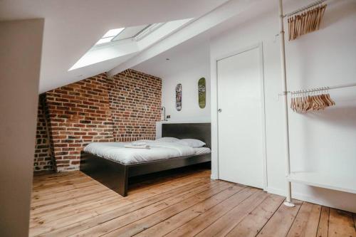 une chambre avec un lit et un mur de briques dans l'établissement Duplex 4pers - 100m du métro - SmartTV - Fibre, à Lille