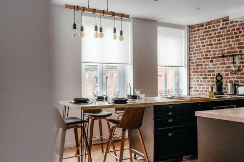 une cuisine avec une table et des chaises ainsi qu'un mur en briques dans l'établissement Duplex 4pers - 100m du métro - SmartTV - Fibre, à Lille