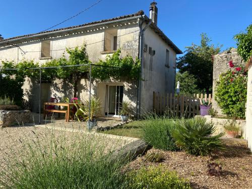 une maison ancienne avec un jardin en face dans l'établissement La Maison des Coteaux, à Chadenac
