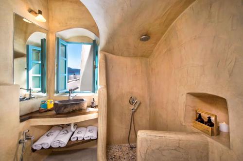 a bathroom with a sink and a tub and a mirror at EverBlue Cave house by Thireon in Oia