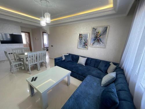 a living room with a blue couch and a table at Appartement de vacances neuf: piscines et plage in Tangier