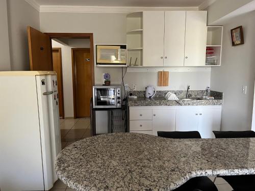 a kitchen with white cabinets and a counter top at Águas da Serra Apart hotel in Rio Quente