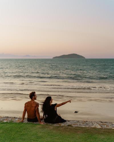 a man and a woman sitting on the beach at Zendaya Resort Beach Sport & Spa in Búzios