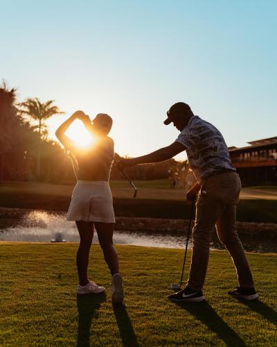 a man and a woman playing golf at sunset at Zendaya Resort Beach Sport & Spa in Búzios