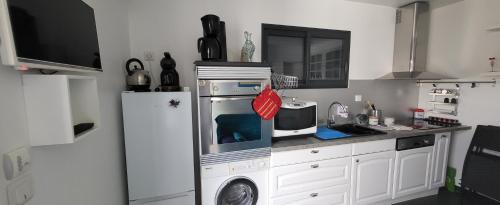 une cuisine avec un réfrigérateur et un micro-ondes dans l'établissement Appartement à 200 m de l'Etang de Thau, à Mèze