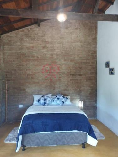 a bedroom with a blue bed with a brick wall at Chalé Pedra Chanfrada 03 in Gonçalves