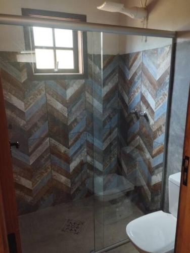a bathroom with a glass shower with a toilet at Chalé Pedra Chanfrada 03 in Gonçalves