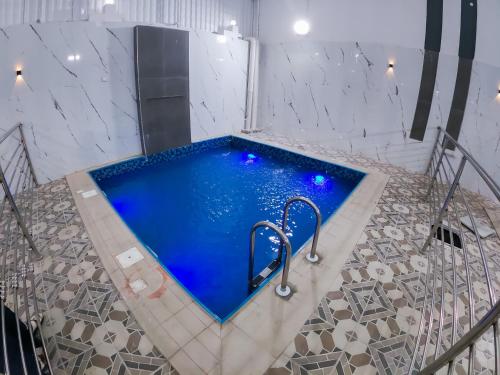 a jacuzzi tub with blue water in a room at Nesto Hotel in Manāwirah