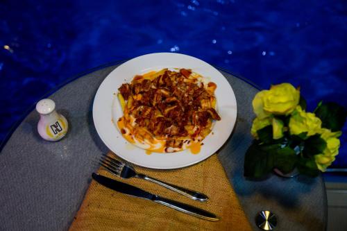 a plate of food on top of a table at Nesto Hotel in Manāwirah