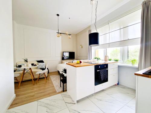 a kitchen and living room with white cabinets and a table at J&W Apartments Grójecka Glam Flat in Warsaw
