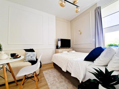 um quarto com uma cama, uma mesa e uma televisão em J&W Apartments Grójecka Glam Flat em Varósvia