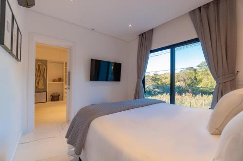 Un dormitorio con una cama grande y una ventana grande. en Kamabre Luxury Villas, en Foz do Iguaçu