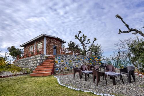 a group of chairs and tables in front of a house at Ransuli mountain stay jungle camping in Dehradun