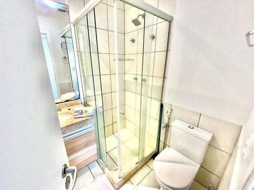 uma casa de banho com um WC e uma cabina de duche em vidro. em Belíssimo Apartamento no resort do Beach Park - By Ideal Trip Hospedagens em Aquiraz
