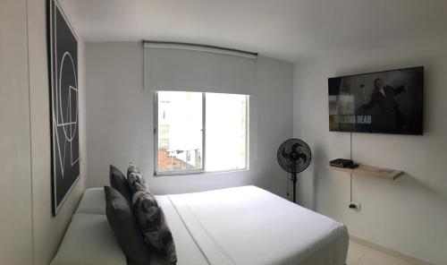 a white bedroom with a bed and a window at Estudio confortable especial para viajeros Wifi Tv Streaming in Bucaramanga