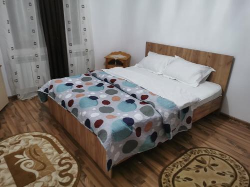 1 dormitorio con 1 cama con un edredón colorido en Moldovița Residence, en Moldoviţa