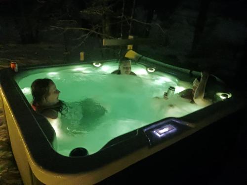 a person sitting in a jacuzzi tub at night at Lapland Hygge in Rovaniemi