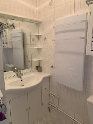 une salle de bain blanche avec un lavabo et un miroir dans l'établissement Joli studio proche plage du Môle, au Cap d'Agde