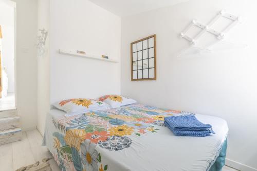 a white bedroom with a bed with a floral blanket at Belle maison bleu azur in Six-Fours-les-Plages