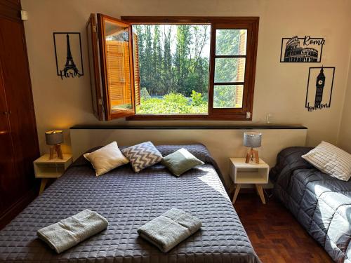 um quarto com uma cama com duas almofadas e uma janela em Cervantes - Casa de huespedes - Chacras de Coria em Ciudad Lujan de Cuyo