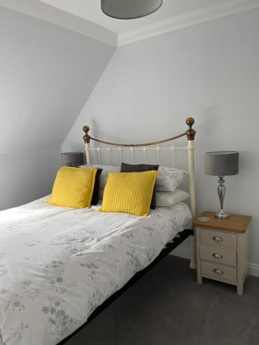 een slaapkamer met een bed met gele kussens en een tafel bij Tigh na Drochaid, Glen Nevis Entire Apartment in Fort William