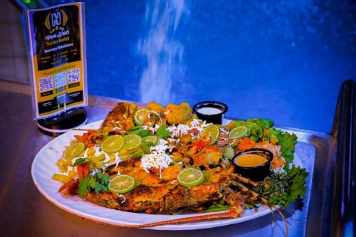 a plate of food on top of a table at Nesto Hotel in Manāwirah