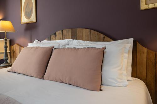 a bed with white pillows and a wooden headboard at Château La Gravière in Vertheuil-en-Médoc
