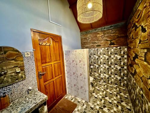 a bathroom with a shower and a wooden door at Sunny Rose Bungalows Gili Air - Adults only in Gili Air