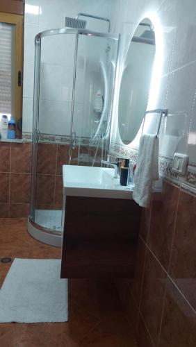 un bagno con lavandino e doccia con specchio di RoAr Apartment a Golem