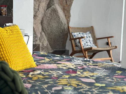 een slaapkamer met een bed met een geel kussen en een stoel bij Villa on the Rocks in Ko Tao