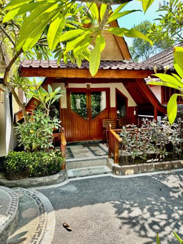 a house with a wooden door and some plants at Sunny Rose Bungalows Gili Air - Adults only in Gili Air