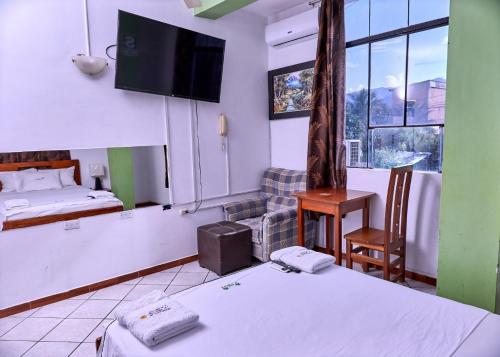 ein Hotelzimmer mit 2 Betten und einem TV in der Unterkunft HOSPEDAJE LA MERCED in Juanjuí