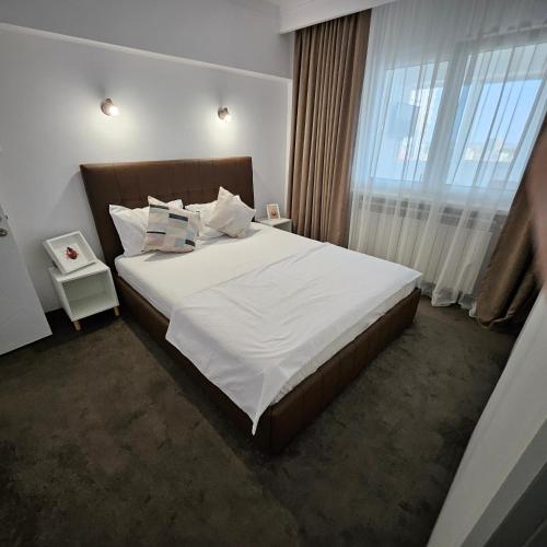 een slaapkamer met een groot bed met witte lakens en kussens bij Cliff Sunrise Apartment in Constanţa